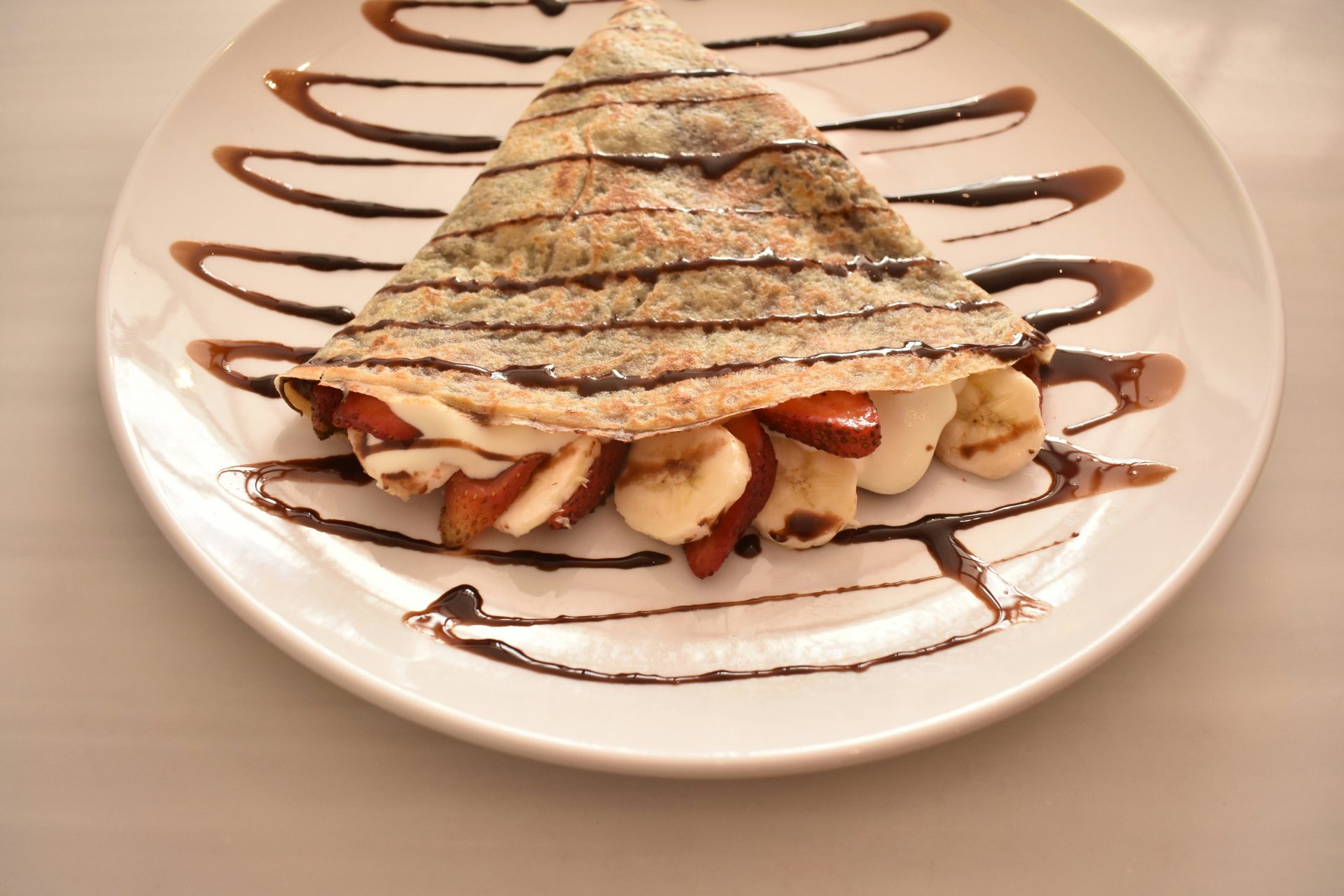 Ein weißer Teller mit einem mit Schokolade überzogenen Dessert darauf.